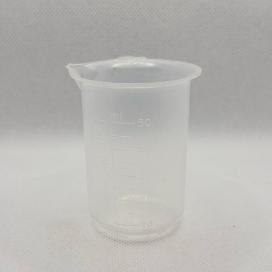 A translucent plastic measuring beaker with a pouring spout, featuring printed measurement markings in milliliters up to 50 ml, set against a light gray textured background.