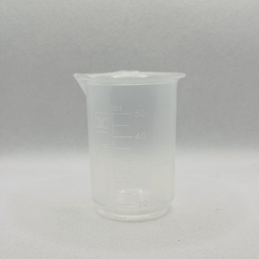 A small translucent plastic beaker with printed measurement markings in milliliters, shown against a light gray textured background.