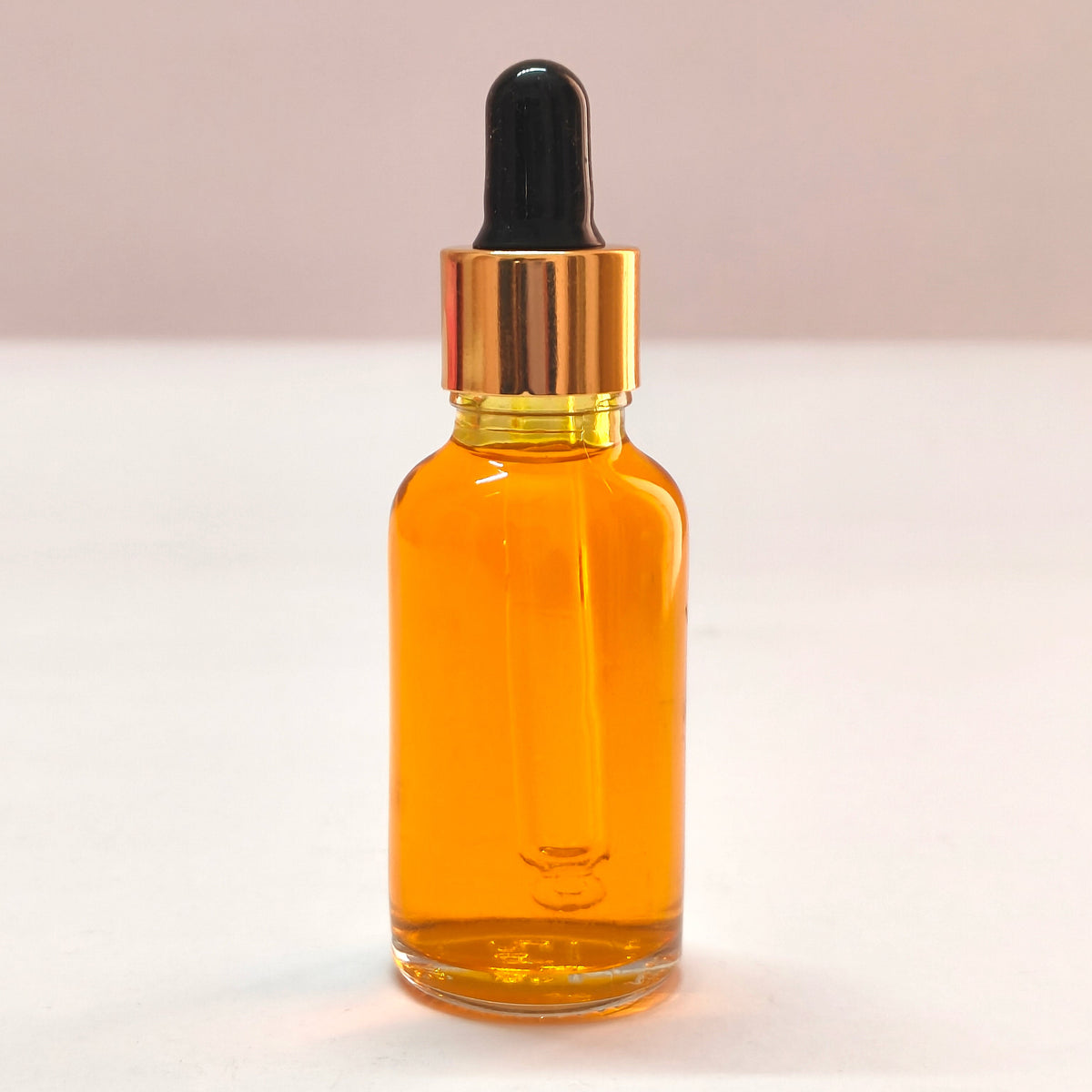 Amber glass dropper bottle with black cap on a white background