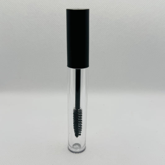 A clear cosmetic tube with a black cap and a black spoolie wand applicator inside, shown on a light gray textured background.