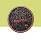 Wooden bowl filled with black seeds / Karboga Arisi on a green background