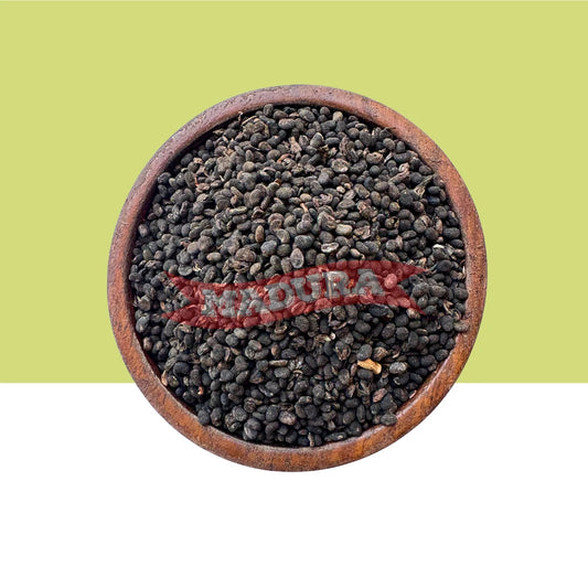 Wooden bowl filled with black seeds / Karboga Arisi on a green background