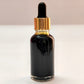 Black dropper bottle with gold cap on a white background
