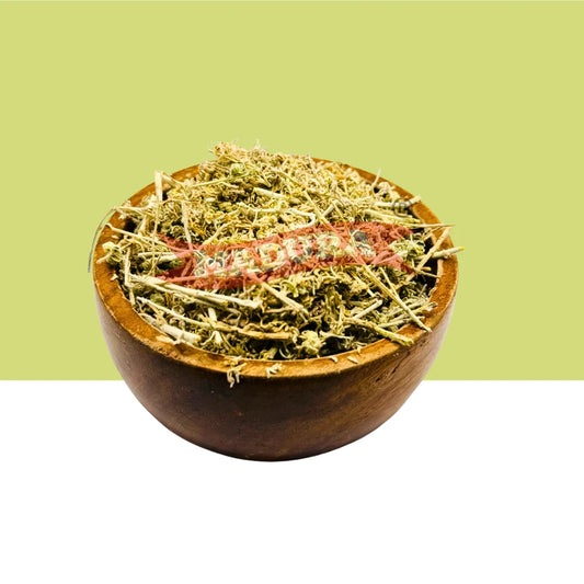 A small round wooden bowl filled with Marikolunthu dried, with a red string wrapped around the contents, set against a split light green and white background.