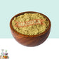 Wooden bowl filled with Marikolunthu Powder on a light blue background