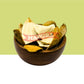 A top-down view of dried Orange Peel pieces arranged in a round brown bowl, with a red banner across the center reading 'MADURA'. The background is split horizontally with a light yellow-green upper half and white lower half.