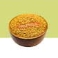 A wooden bowl filled with golden-yellow fenugreek seeds, centered against a split light green and white background.